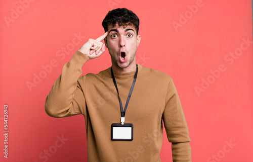 adult man looking surprised, realizing a new thought, idea or concept with an acccess identity card photo