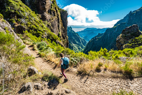 Woman with backpack hiking along scenic hike trail to Pico Ruivo in the late morning. Pico do Arieiro, Madeira Island, Portugal, Europe.