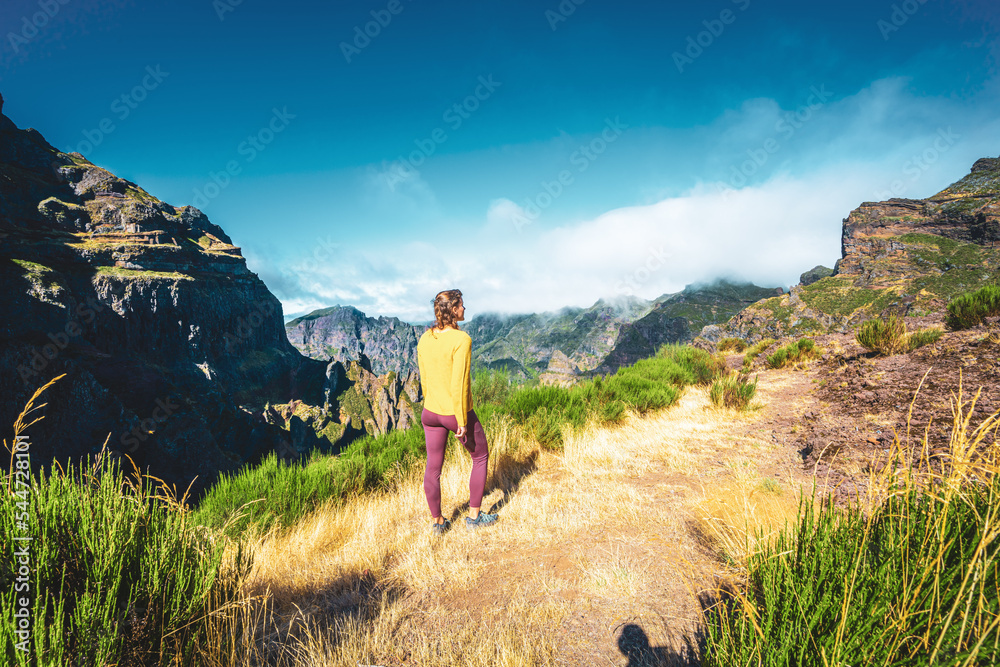 Fototapeta premium Woman enjoying mountain scenery from very scenic view point along hike trail to Pico Ruivo in the morning. Pico do Arieiro, Madeira Island, Portugal, Europe.