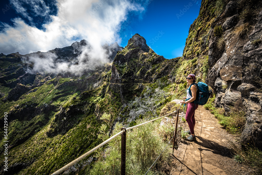 Hiker with backpack enjoying the view along very scenic hike trail to Pico do Ariero in the afternoon. Verade do Pico Ruivo, Madeira Island, Portugal, Europe.