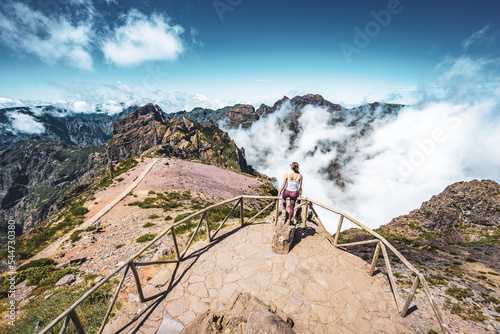 Sporty woman enjoying the fabulous view on Pico Ruivo from the viewpoint on Pico do Ariero in the afternoon. Verade do Pico Ruivo, Madeira Island, Portugal, Europe.