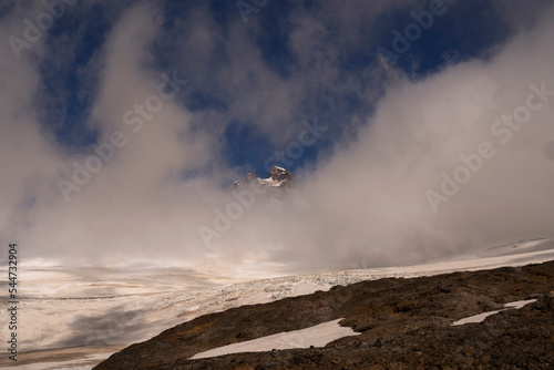 Alpine landscape. View of Tronador hill rocky peak and glacier Castaño Overo snow and ice field under a cloudy sky.