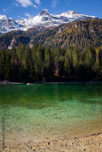 The crystal clear waters of Lake Tovel, Trentino Alto Adige, Italy. Vertical shot with snowy mountains in the background.