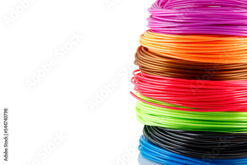 Colorful rolled filaments for 3D pen isolated on white. Closeup of plastic bright wires for 3D printer lying on table. Concept of children's entertainment and creativity. photo