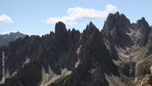 Female traveler looks through binoculars at mountain landscape near Tre Cime di Lavaredo. Tourist stands on top edge of mountain near gorge aerial view photo