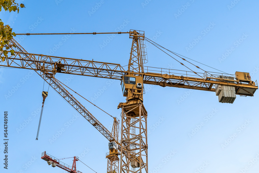 Construction site with yellow cranes against blue sky. Industrial background. Modern skyscrapers. Unfinished construction