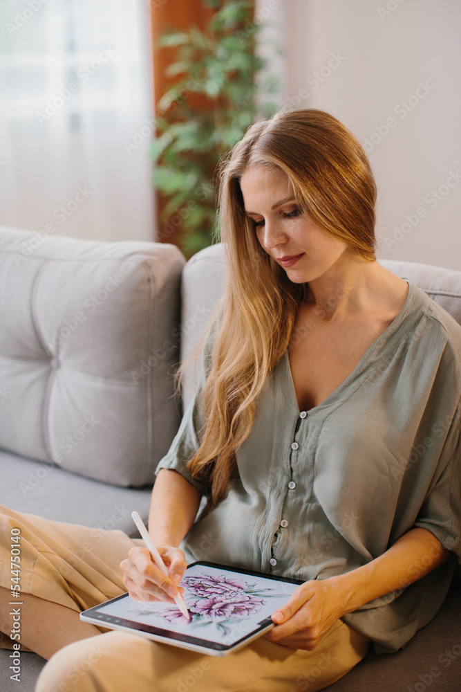 Happy young designer drawing on a graphics tablet with a stylus pen. Creative young freelancer working in her home office. Happy young designer drawing on a graphics tablet with a stylus pen. Creative young freelancer working in her home office.