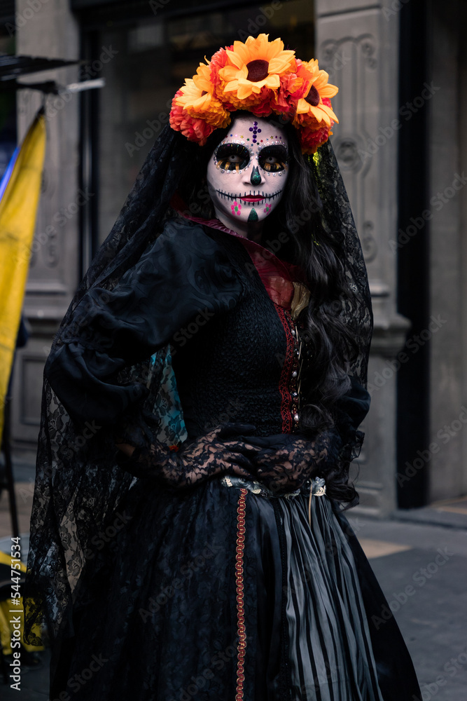 Mujer disfrazada de catrina con velo negro y arreglo floral en la