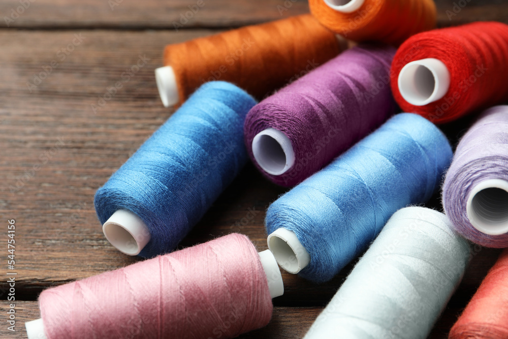 Different colorful sewing threads on wooden table, closeup Different colorful sewing threads on wooden table, closeup