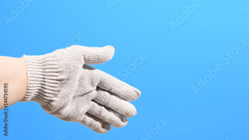 Hand in a working construction cotton glove on a blue background. High quality photo