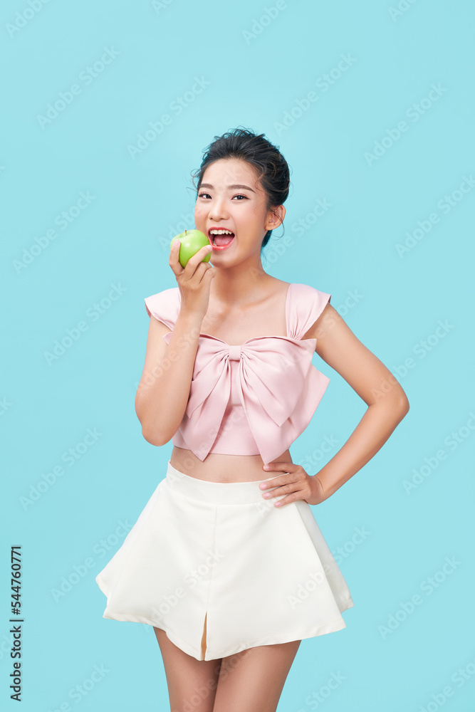 Woman holding and eating fresh green apple on cyan background. Woman holding and eating fresh green apple on cyan background.