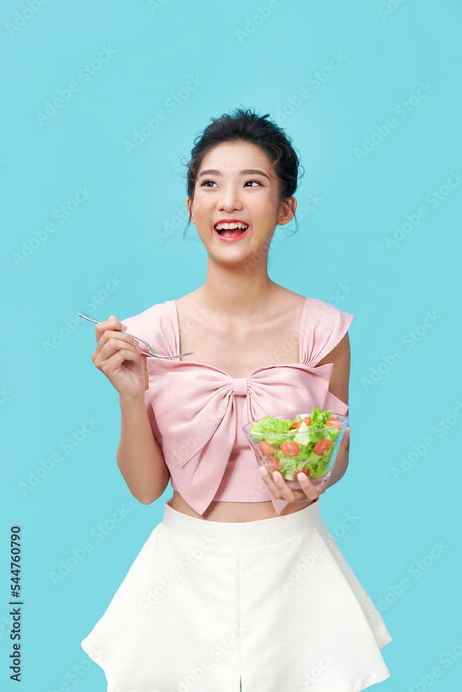 Asian young woman eatiing salad on blue background diet food concept Asian young woman eatiing salad on blue background diet food concept
