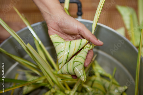  woman hand holding  the triangular sticky rice wrapped with palm leaf or Ketupat Palas	 photo