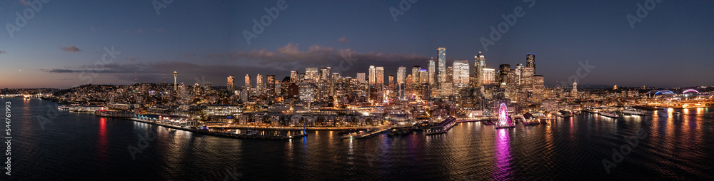 Seattle, Washington, USA - November 2022, night aerial view of illuminated Seattle Downtown and the Waterfront pier area with The Seattle Great Wheel - aerial panoramic view 	