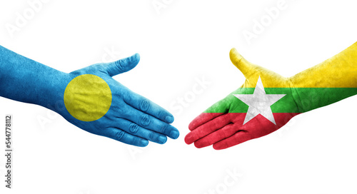Handshake between Myanmar and Palau flags painted on hands, isolated transparent image.