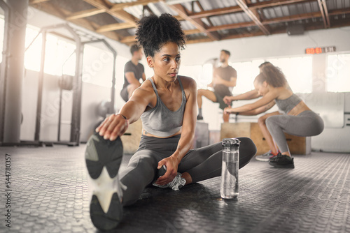 Stretching, fitness and training with black woman in gym with water bottle for exercise, sports and workout. Health, wellness and energy with girl and legs warm up for performance, muscle and strong