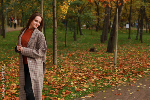 Beautiful young woman in jacket walking in autumn park