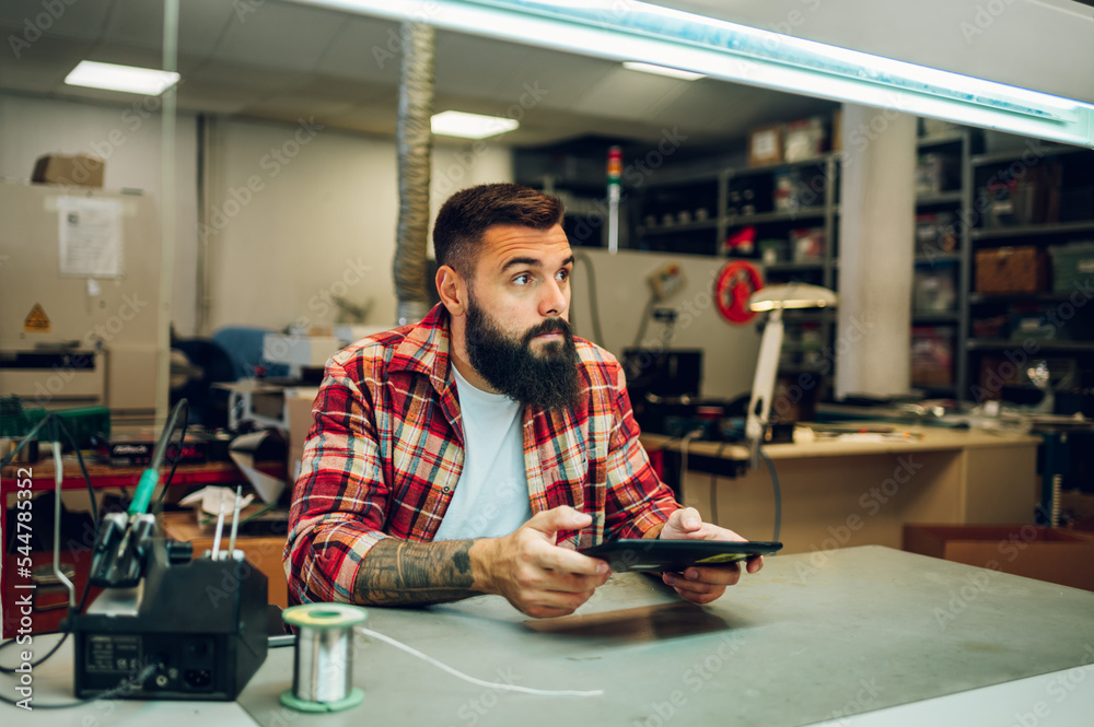 Electronics engineer working in a professional workshop and using a tablet Electronics engineer working in a professional workshop and using a tablet