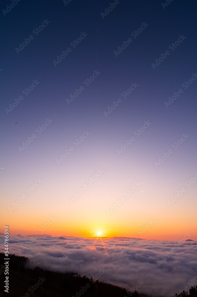 快晴の朝の雲の上に昇る太陽。日本の北海道の美幌峠で。