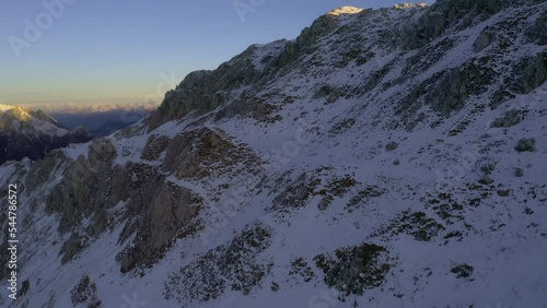 Majestic drone flight over snowy peak of Viezzena Mountain in Dolomites during golden sunrise photo