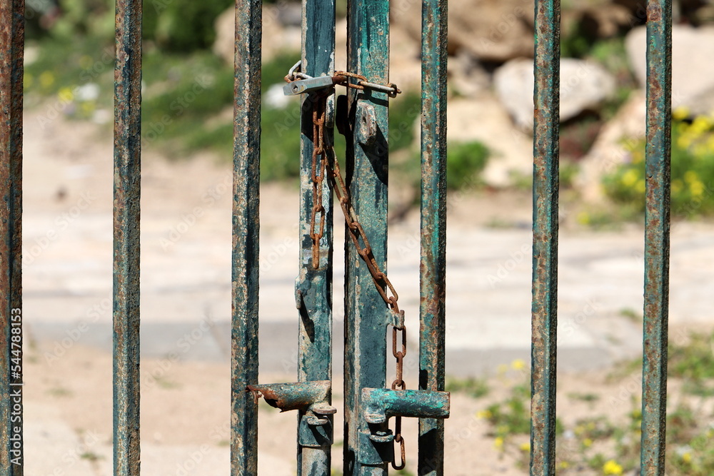 A rusty padlock hangs on a closed gate. A rusty padlock hangs on a closed gate.