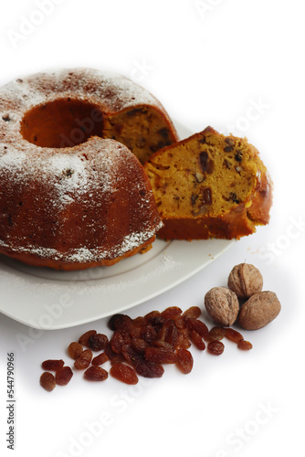Homemade sliced pumpkin bundt cake with raisins and walnuts isolated on white background