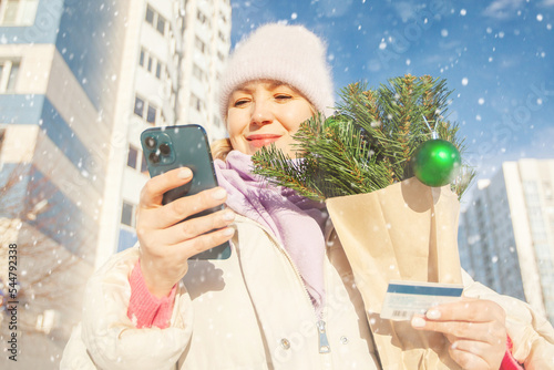 adult woman with shopping and phone. a woman pays with a card. new year christmas