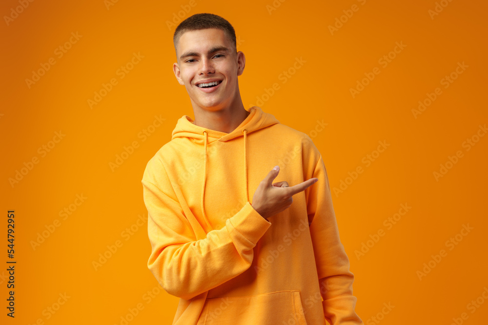 Handsome young man pointing to copy space on a yellow background Handsome young man pointing to copy space on a yellow background