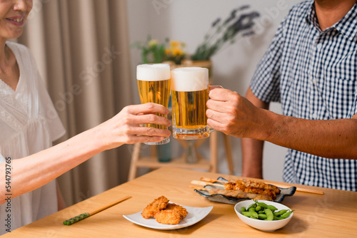 ビールで晩酌をするミドル女性とミドル男性 夫婦の食事イメージ