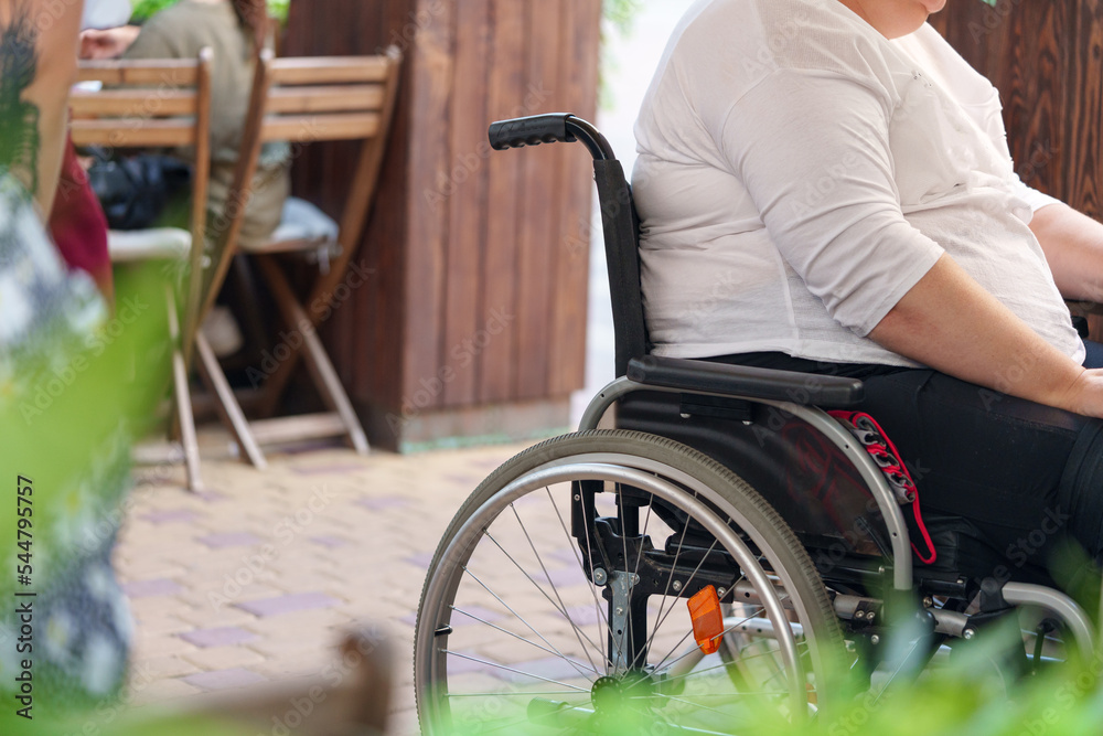 Obraz premium Unrecognizable woman with disability sitting in wheelchair in the street close up