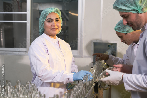 Asian People factory worker or expert quality staff is checking bottles line for beverage