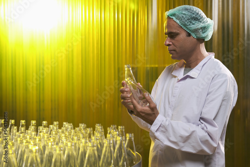 South Asian senior male factory worker or expert quality staff is checking bottles line for beverage