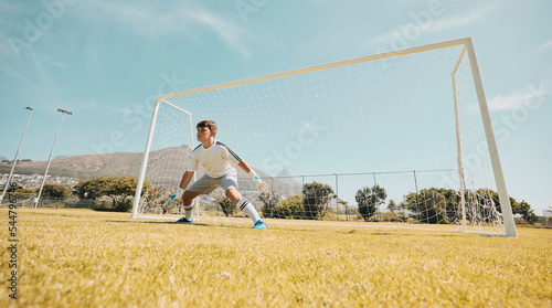 Boy, soccer field or goalkeeper in fitness game, exercise match or training competition in sports club, school ground or campus grass. Child, kid or football player in net post on park football field photo