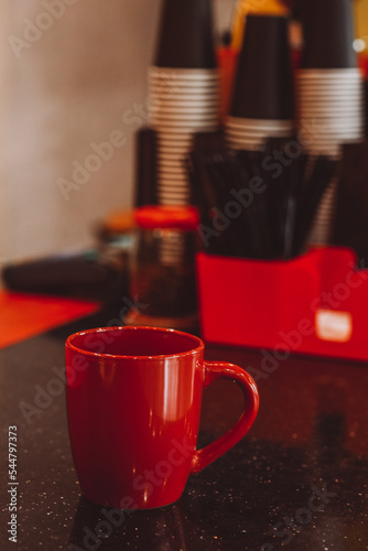 Large red mug for coffee on a black table in a coffee shop