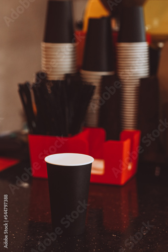 Black disposable cardboard coffee cup in a coffee shop