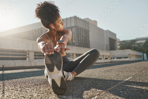 Fitness, city and woman stretching her legs in the street before a cardio workout, running or training. Sports, health and lady doing a warm up stretch for an outdoor exercise in the urban town road.
