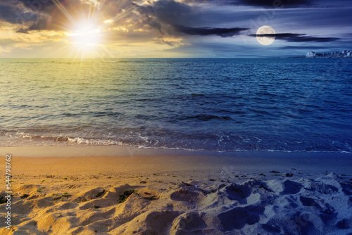 sunny morning scenery at the sea. day and night time change concept. calm waves washing the sandy beach at twilight. transparent water and bright blue sky with sun and moon. summer equinox