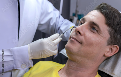 Handsome Caucasian man doing beauty face injection in Beauty Clinic, beautician inject filer on man face