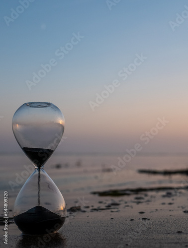 Sand hourglass at the beach at sunset photo