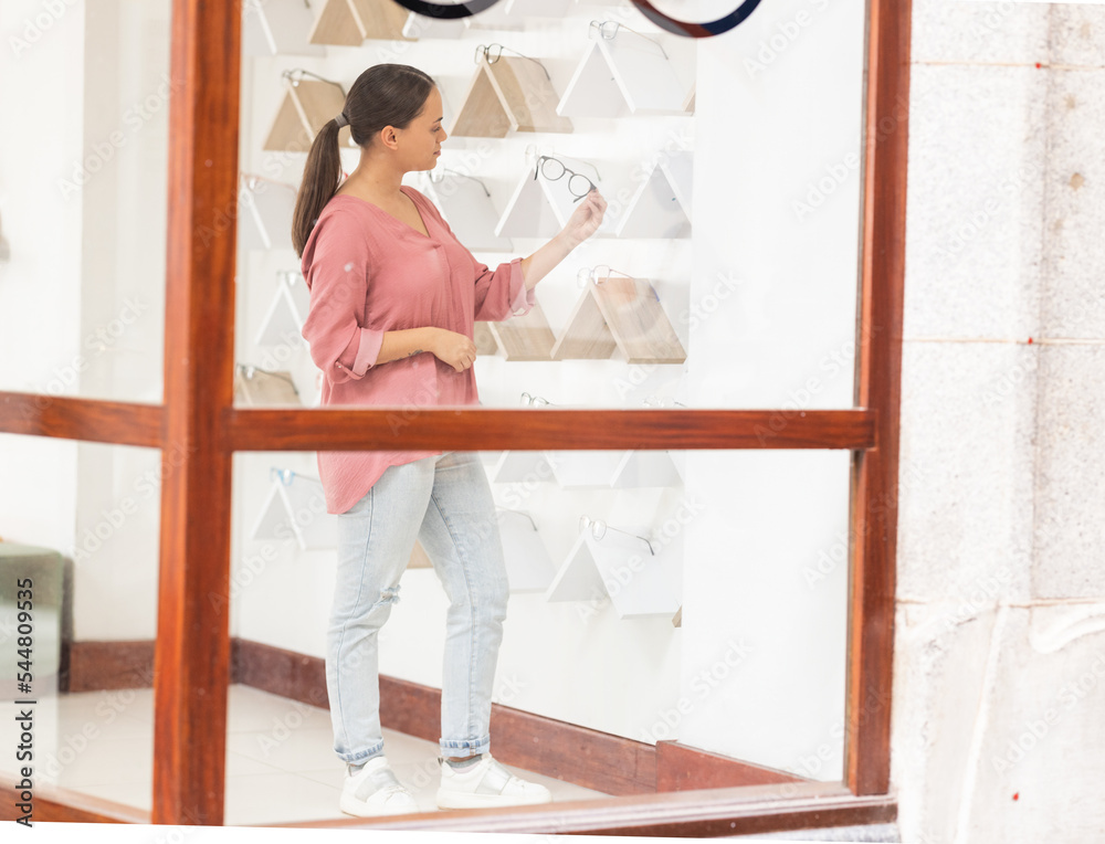 Shopping, retail and woman with glasses at a store for quality choices, frames on promotion and eye care. Decision, girl or customer checking options for better eyesight or clear vision at optician Shopping, retail and woman with glasses at a store for quality choices, frames on promotion and eye care. Decision, girl or customer checking options for better eyesight or clear vision at optician