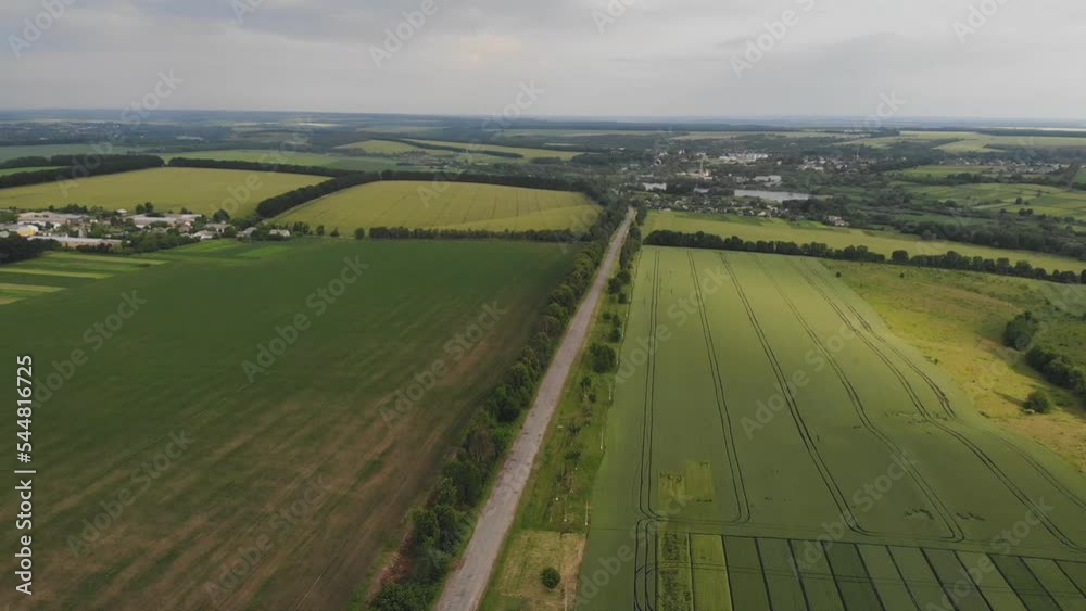 View from a height above the suburban road between the fields, flight over the forest. Summer landscape sunset. original file, without processing. View from a height above the suburban road between the fields, flight over the forest. Summer landscape sunset. original file, without processing.