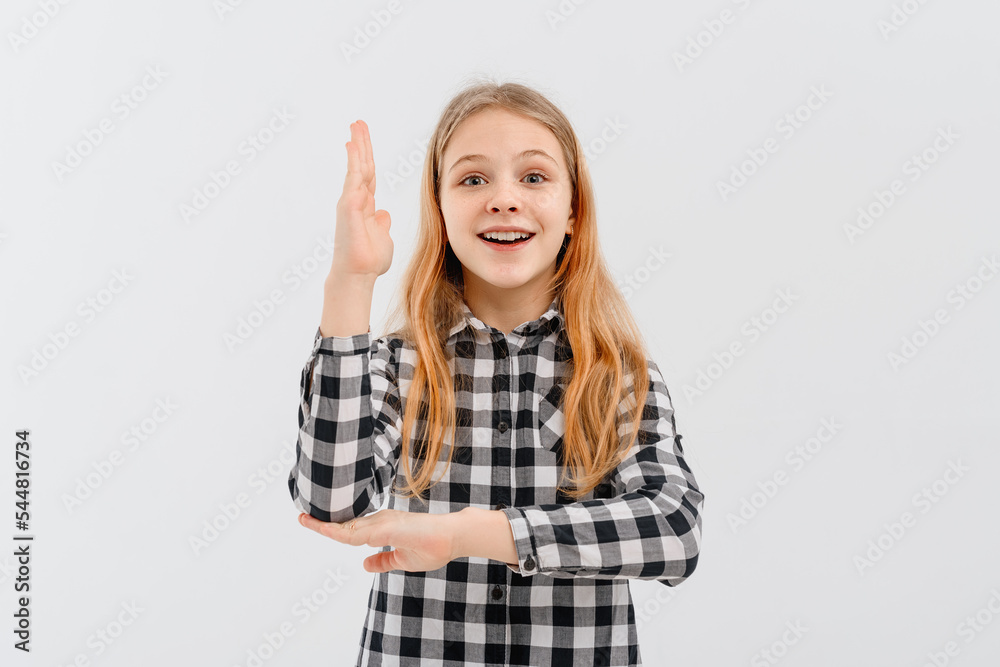 Beautiful teen girl with blonde hair wearing casual yellow t shirt, stands with his hand raised up over white studio background, smiling and gesturing hand. Education and school concept Beautiful teen girl with blonde hair wearing casual yellow t shirt, stands with his hand raised up over white studio background, smiling and gesturing hand. Education and school concept