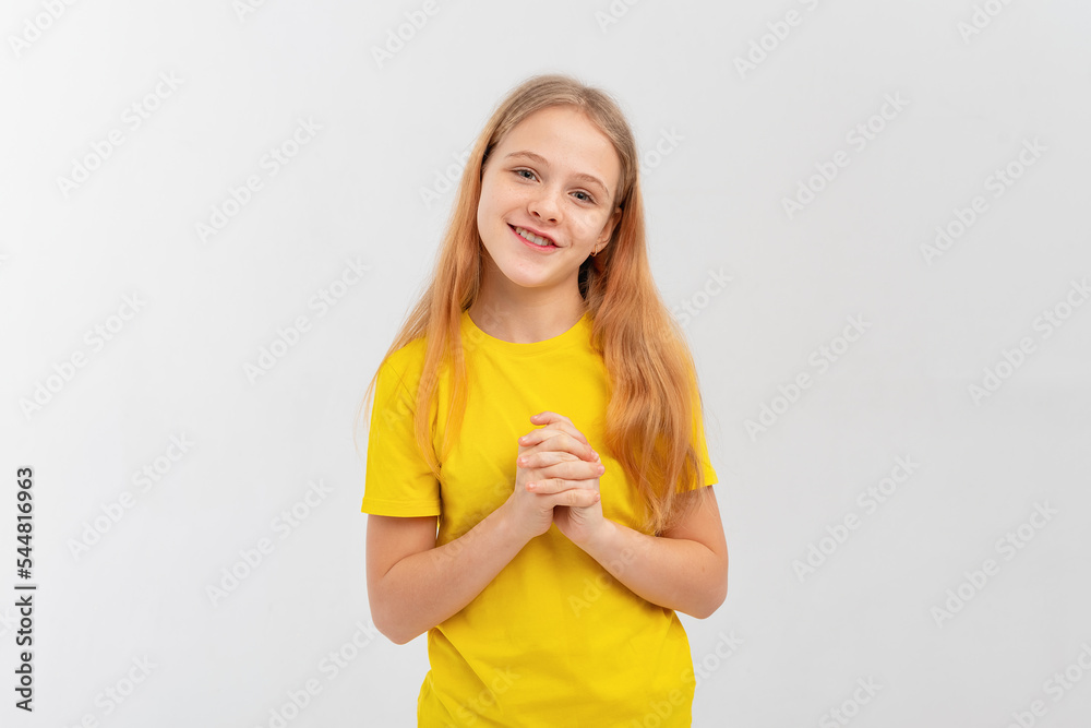 Romantic teen girl daydreaming, looking at camera with dreamy lovely gaze, wears yellow t-shirt, looks happy, stands over white background Romantic teen girl daydreaming, looking at camera with dreamy lovely gaze, wears yellow t-shirt, looks happy, stands over white background