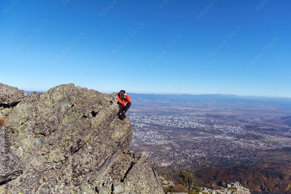 Woman sitting on a rocks high  in the autumn  mountain above the city of Sofia. Vitosha mountain,  ,Bulgaria