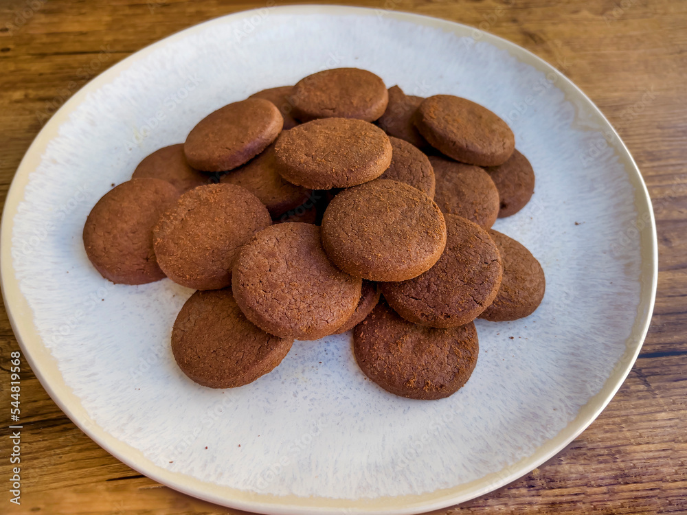 Cacao biscuits in white plate on wooden background Cacao biscuits in white plate on wooden background