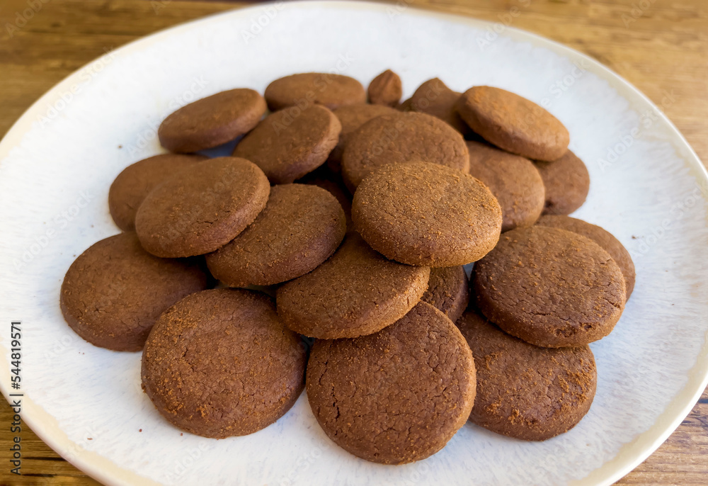 Cacao biscuits in white plate on wooden background