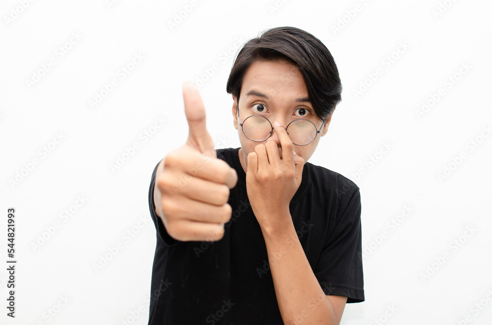 handsome attractive Asian man smiling happily and giving thumbs up as compliment isolated over white background. man giving approval and compliment by gesturing thumbs up. handsome attractive Asian man smiling happily and giving thumbs up as compliment isolated over white background. man giving approval and compliment by gesturing thumbs up.