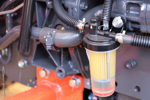 Tractor fuel filter. Transparent fuel filter with black rubber hose mounted on tractor side with copy space. Selective focus