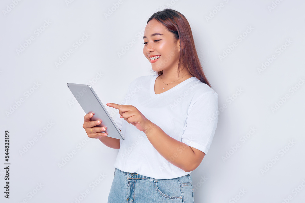 Portrait of smiling young Asian girl in white t-shirt using digital tablet isolated on white background Portrait of smiling young Asian girl in white t-shirt using digital tablet isolated on white background