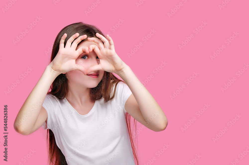 Brunette girl making heart shape  with hands and looking through it